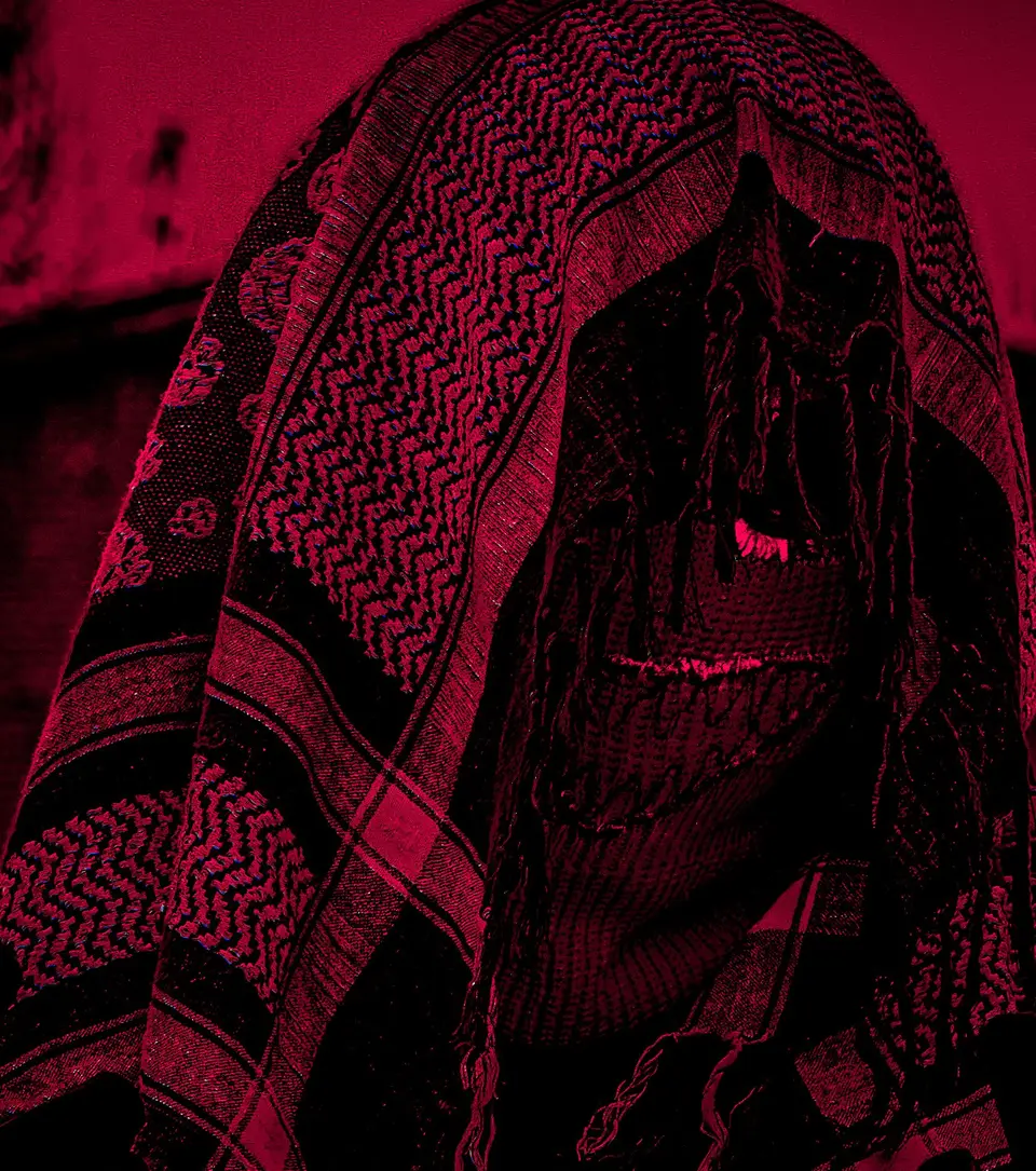 Embroidered ski mask worn under a keffiyeh, red light