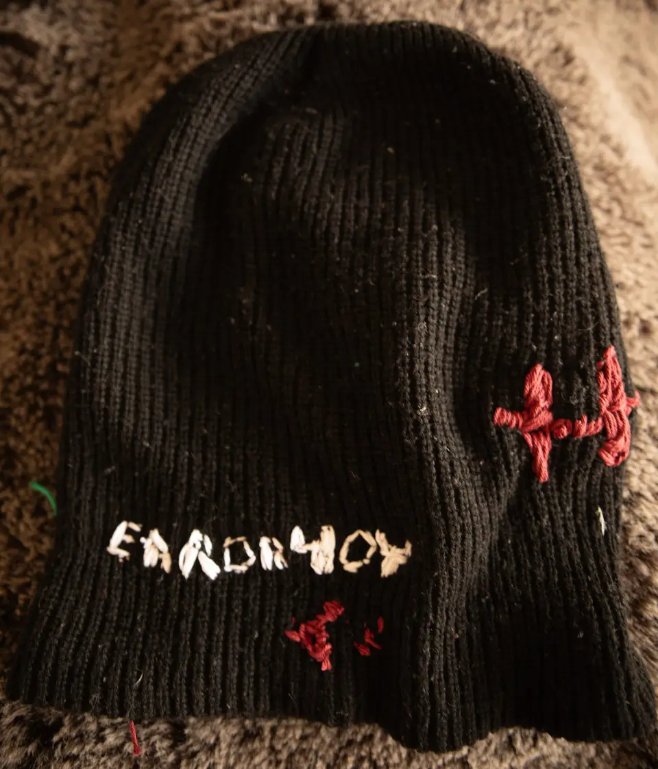 Other side of ski mask Nº 3: letters embroidered in white and small red crosses on black knit